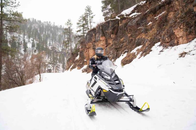 Woman riding a Polaris Adventures Snowmobile in Spearfish Canyon part of the Black Hills Trail System