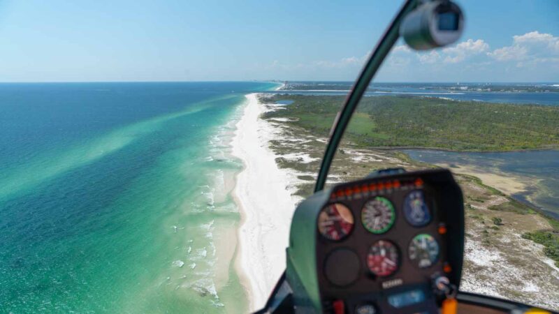 View from the cockpit of a Panama City Beach Helicopter Ride - Heli controls in the foreground and aqua water and white sand beaches