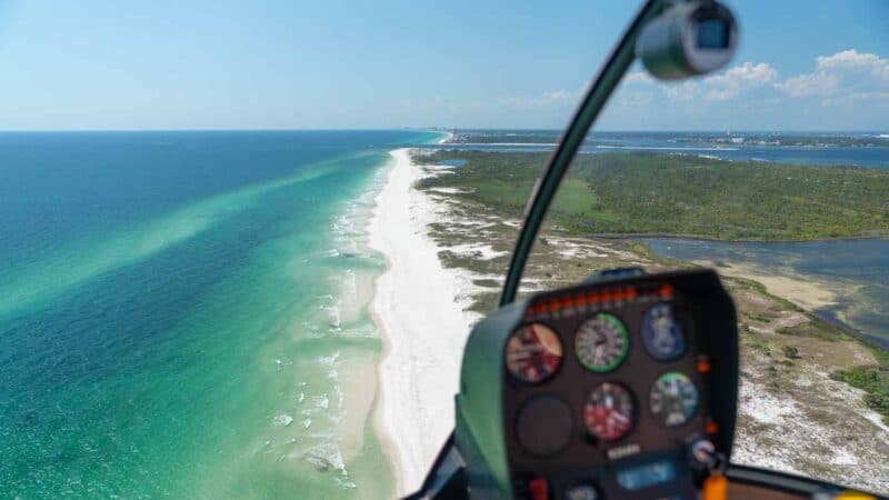 View from the cockpit of a Panama City Beach Helicopter Ride - Heli controls in the foreground and aqua water and white sand beaches