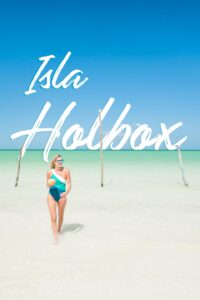 woman standing in front of wooden posts in the waters of Isla Holbox - Pinterest pin for Isla Holbox Travel Guide