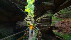 woman in a yellow jacket walking in witches gultch - things to do in Wisconsin Dells on a rainy day