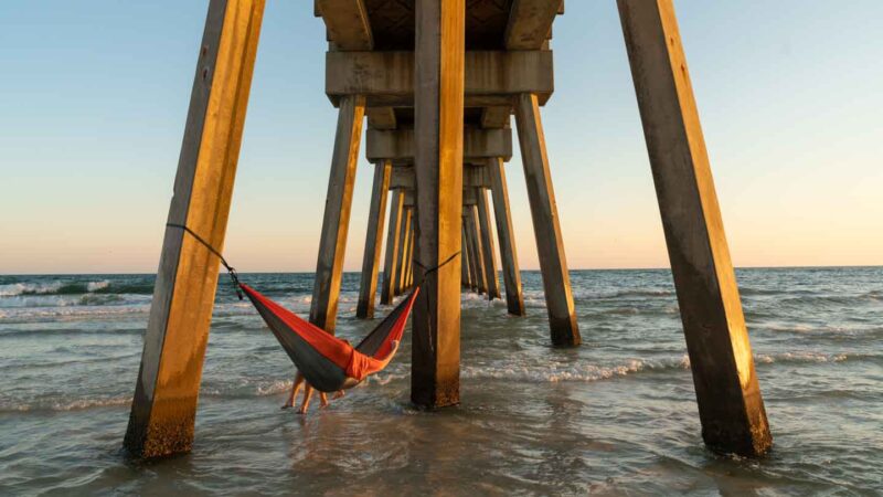 view under the city park pier in Panama City Beach with a couple sitting in a hammock- Top photo and tourist spots in PCB Florida