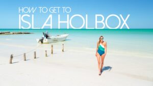 woman standing in front of a boat on Holbox Island - Featured Image for How to get to Isla Holbox Mexico