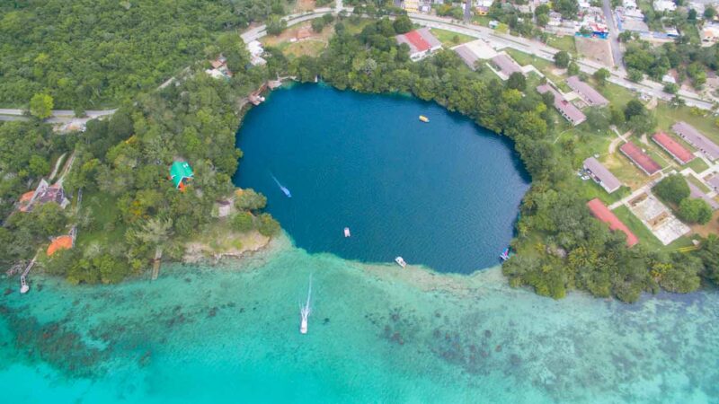 Aerial View of Cenote Azul in Bacalar Mexico - Dark blue sinkhole surrounded by shallow aqua colored water