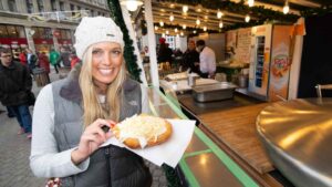 Woman holding a Langos - a fried dough filled with cheese served at a Budapest Christmas Market