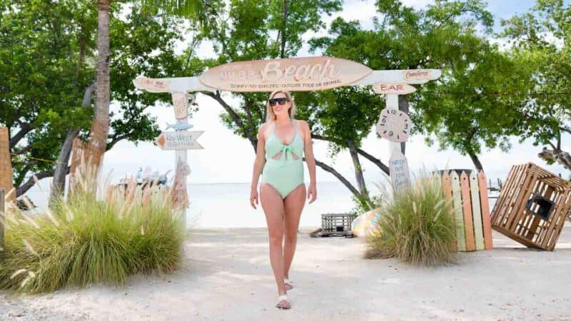 woman standing in front of the MM88 beach sign at mile marker 88 on the overseas highway during a Florida Keys road trip