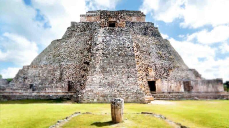 Main Pyramid of Uxmal MMayan Ruin Site in Mexico - Large stone structure with small stone cylinder in front