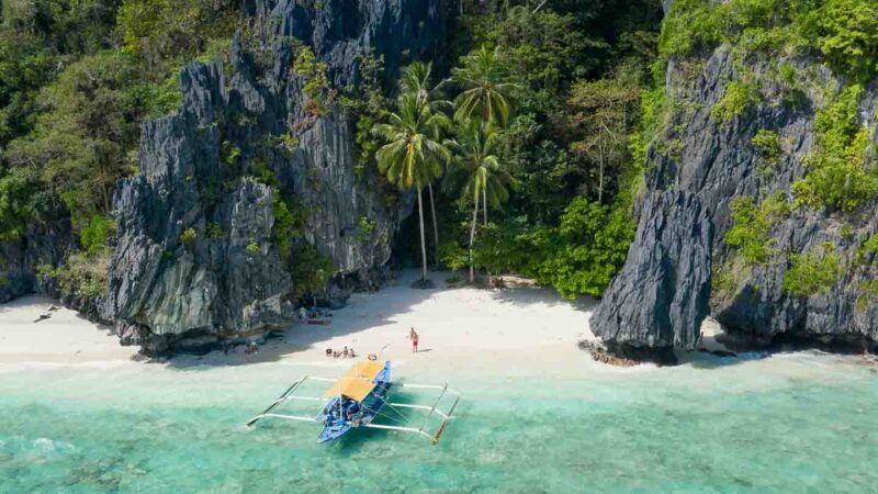 White sand beach with a traditional Filipino Boat anchored on a Island Hopping trip in the Philippines