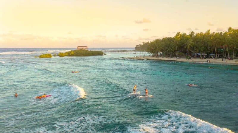 surfers riding waves while surfing in Siargao Philippines