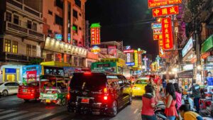 View of a busy street in Chinatown in Bangkok with neon sighs and Chinese Charters