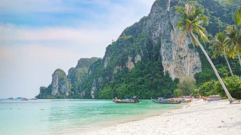 White sand and Palm trees at Tonsai Beach with tall cliffs of Koh Phi Phi in the background