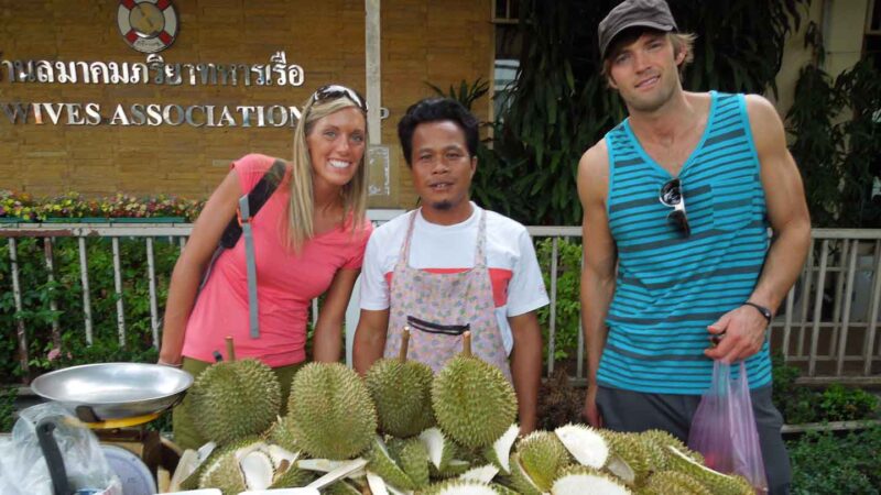 tourists standing with a durian vendor in Thailand - Foods to try in Bangkok