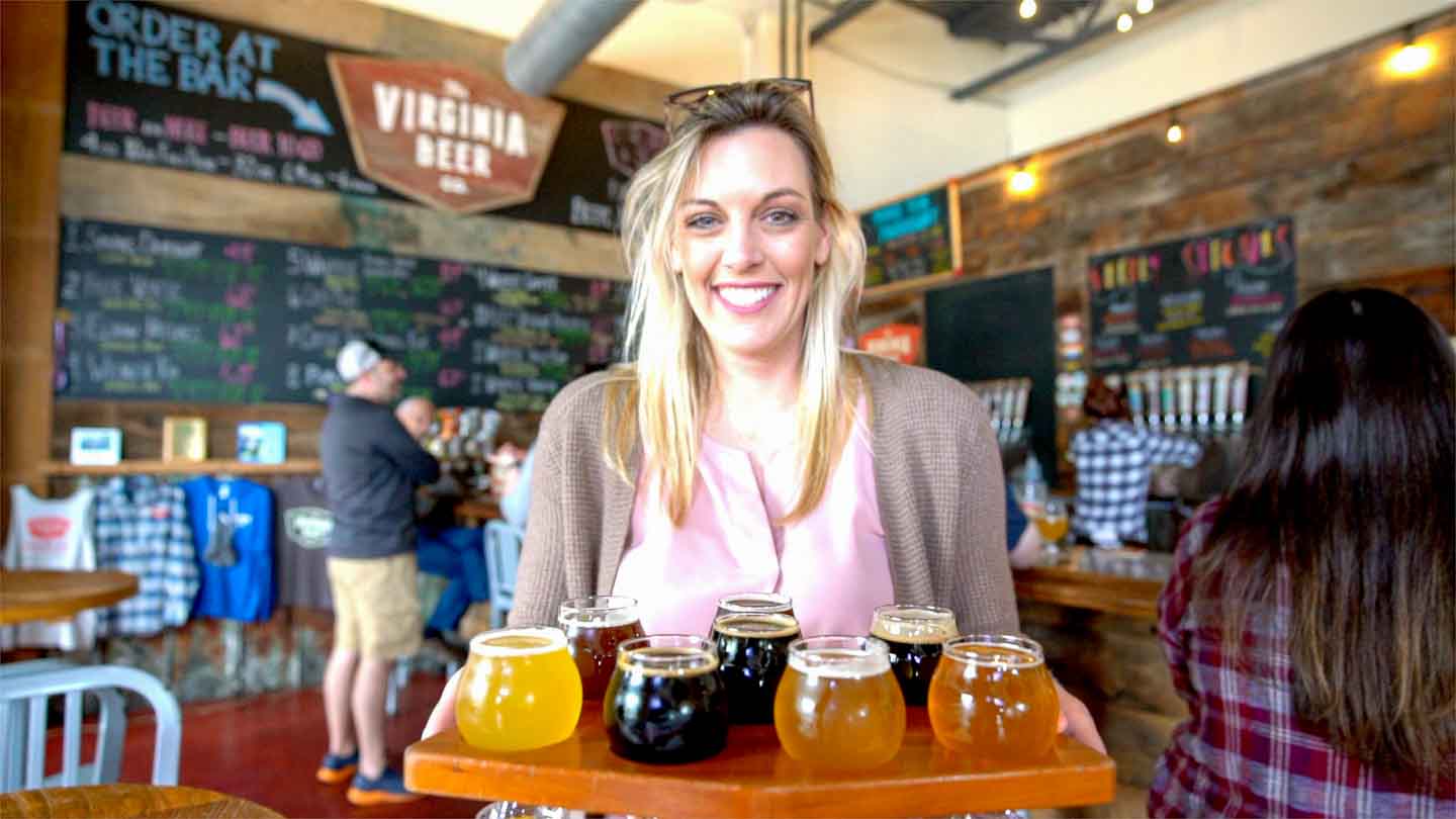 Woman carrying a flight of beers from the Virginia Beer Company in Williamsburg Virginia
