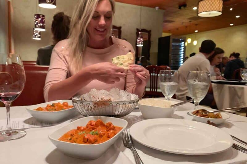 Woman dining at Nawab Indian Food - Plates of Tika Masala and naan bread - Top Indian food in Williamsburg