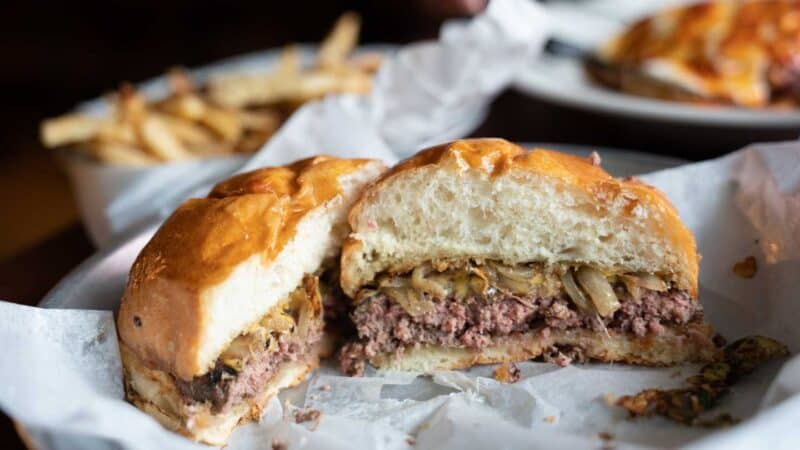 Hamburger from Camino Restaurant cut inhalf served with Brussels sprouts and french fries