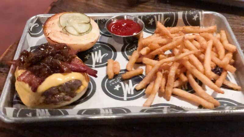 Tray of bacon topped Burgers, fries and condiments from Merriment Social in Milwaukee