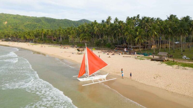 sailboat with a red sail parked on Nacpan Beach