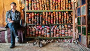 Man sitting infront of hundreds of colorful leather shoes - multiple colors - Things to see in Morocco