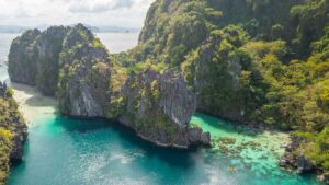 drone view of a yellow kayak in the big lagoon of El Nido surrounded by large rock formations