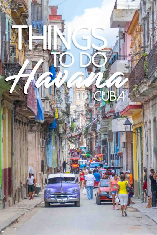 purple car on a narrow street filled with people - Things to do in Havana Pinterest Pin