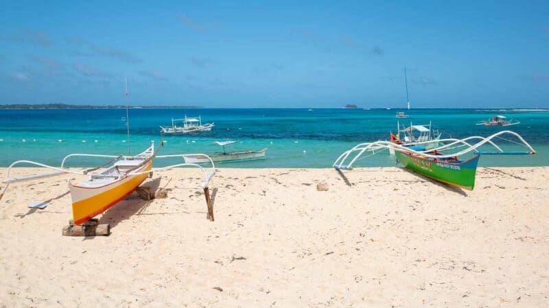 two traditional Filipino boats beaches on the shores of Daku Island - Siargao Philippines