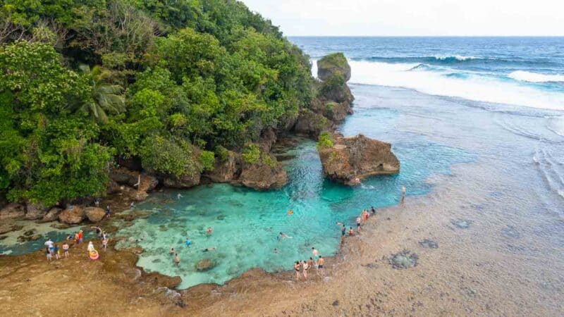 Aerial drone photo of the Magpupungko rock pools with rock formations surrounding the clear shallow waters