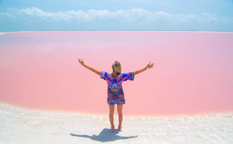 Woman with arms raised infront of Las Coloradas Pink Lakes