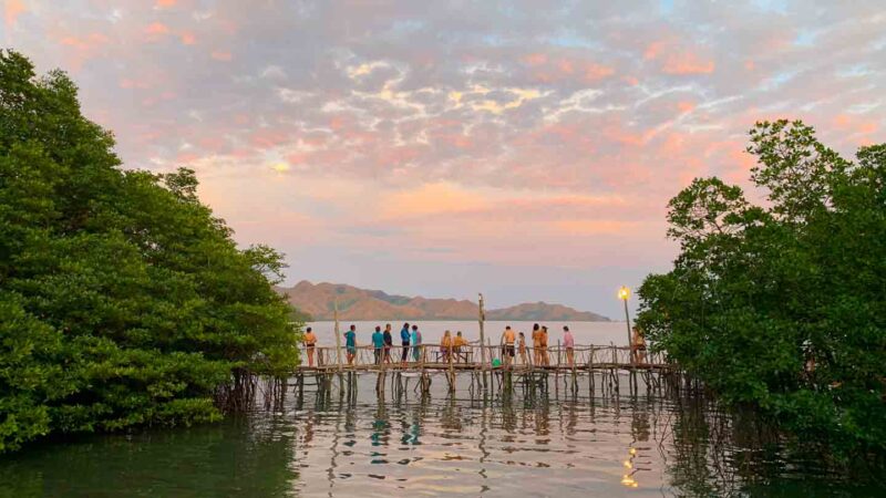 Group of people sitting on the pier of the Coron Hot Springs at Sunset