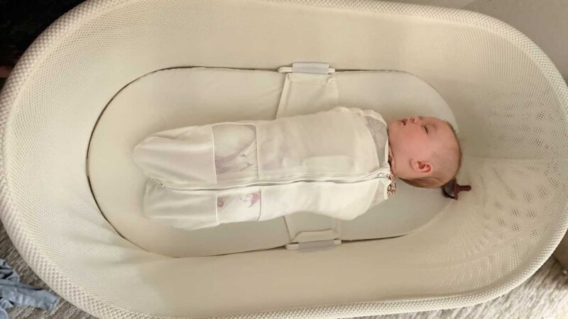 Newborn baby sleeping in the Snoo zipped up in the Snoo Sack