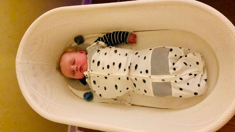 6 month old sleeping in the Snoo bassinet with one arm out