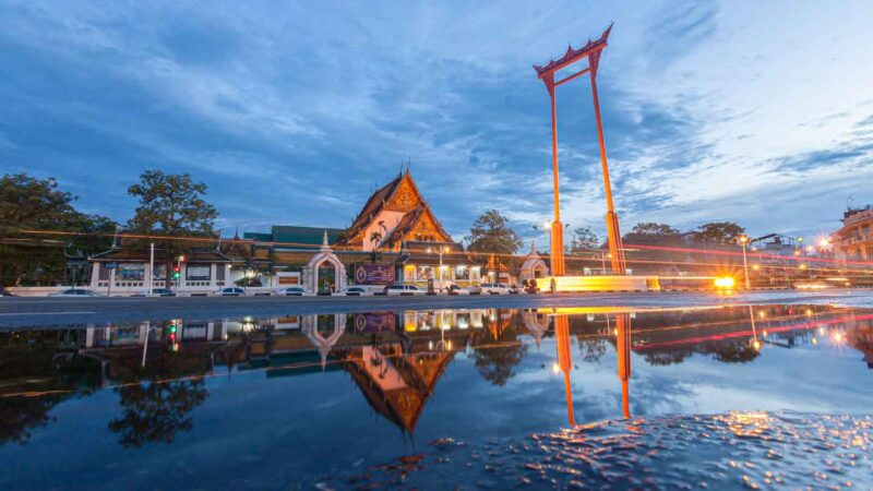Reflection in a puddle of the Wat Suthat Temple in Bangkok's China Town with the Giant Swing located in front