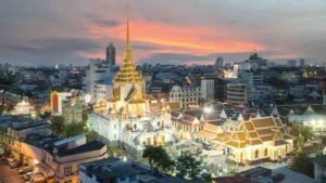 Large White temple named Wat Tramit with multiple golden stupas illuminated at night in the city of Bangkok
