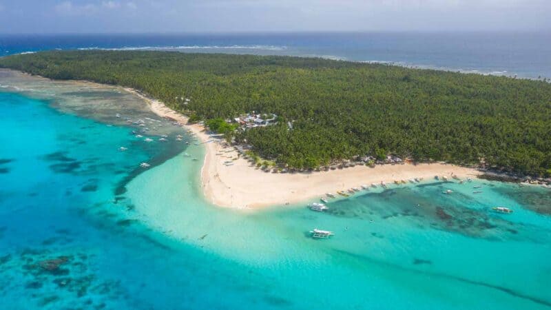 Wide drone photo of Daku Island with white sand and turquoise color waters