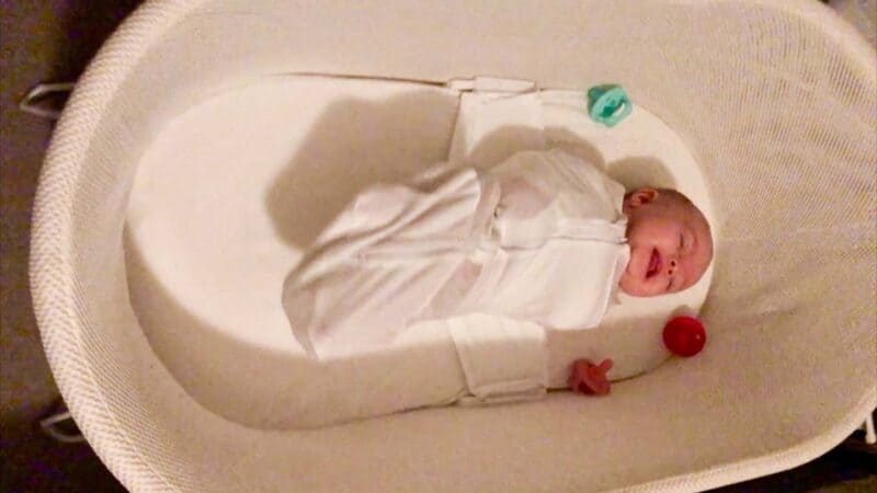 Baby in bassinet with pacifers