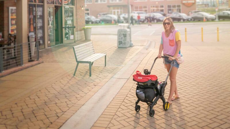mother pushing Doona car seat stroller in front of a restaurant