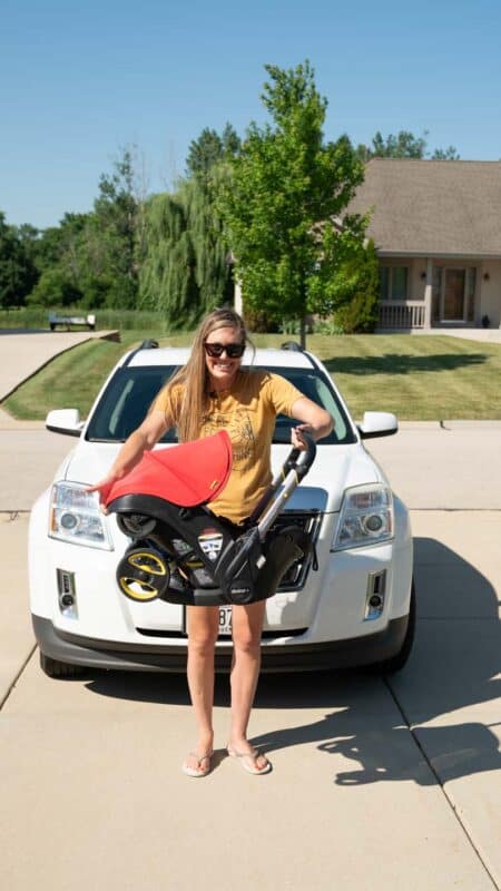 woman folding the Doona stroller in front of car in a driveway