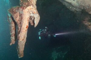 Diver with a light next to the Angelita Stalactite which gives the cenote its name