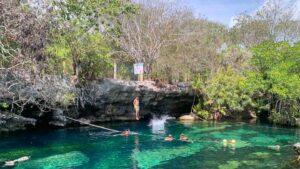 two people jumping from the cliff of Cenote Cristalino