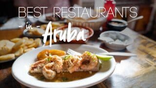 Plate of seafood surrounded with side dishes at one of the top restaurants in Aruba - Featured image with white text over