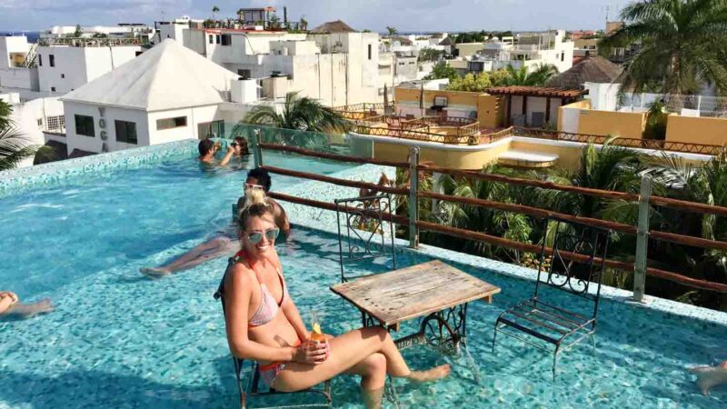 woman sitting on a chair in a rooftop pool at a hotel in Playa del Carmen