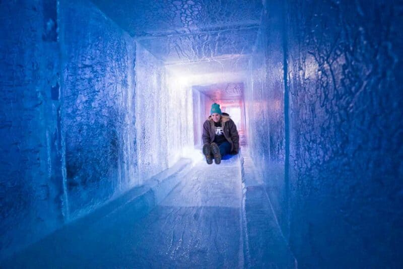 girl sliding on an ice slide at the ice castles