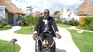 A butler dressed in black riding a bike at Sandals Resorts Barbados location