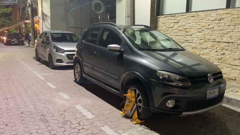 black car rental parked with a parking boot on in the streets of Playa del Carmen