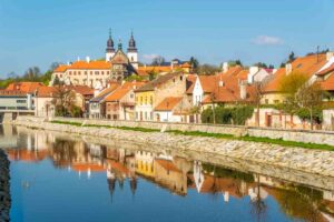 View of the white buildings with orange roofs in the charming town of Třebíč in Czech Republic reflecting in the waterway