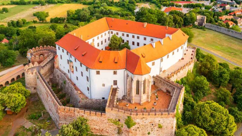 Aerial view of the white building and orange roof of the Siklos Castle in Hungary