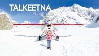 woman standing in front of a white and red plane on Denali during a scenic flight - Top things to do in Talkeetna Alaska featured image