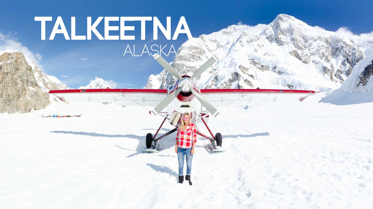 woman standing in front of a white and red plane on Denali during a scenic flight - Top things to do in Talkeetna Alaska featured image
