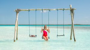 woman in a red swimsuit sitting on a water swing at Cenote Cocalitos in Bacalar