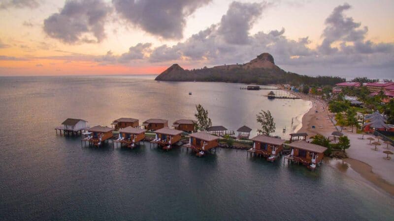 Overwater bungalows at Sandals Grande St. Lucian during a pink and purple sunset