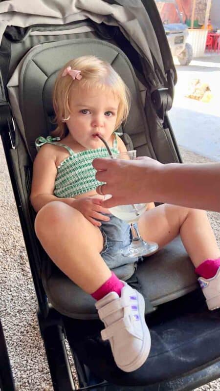 toddler girl drinking water in the stroller